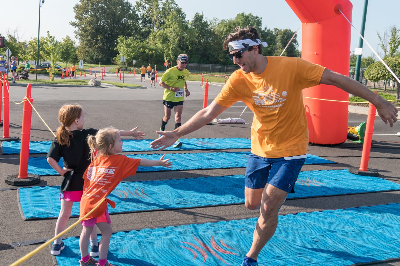 Participant giving a child a high-5 at the finish line
