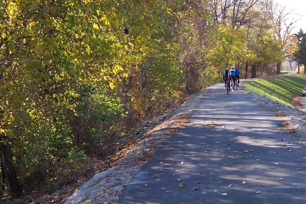 three riding bikes along the river greenway